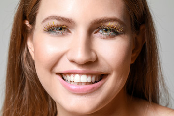 Fototapeta premium Young woman with creative eyelashes on grey background, closeup