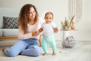African-American mother teaching her little baby to walk at home