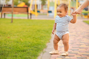 Cute little baby learning to walk outdoors
