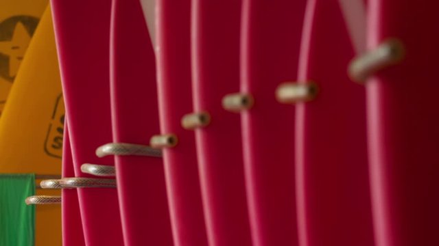 Rack focus along a row of red surfboards in a store