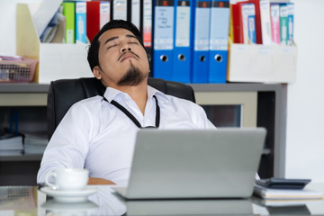 business man sleeping on working desk between using laptop computer