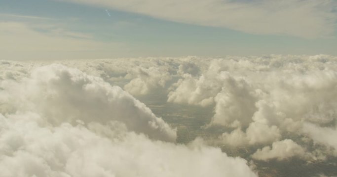 Aerial shot, day, slow pan to right examing top layer of clouds, drone