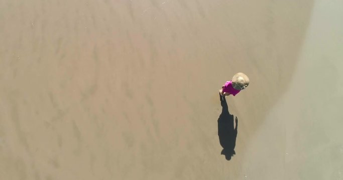 Mujer pasea en solitario en arena dorada y dron graba en vertical