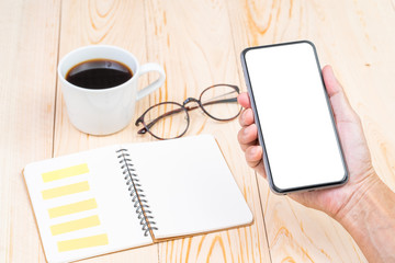 Hand holding blank screen smart phone with office table background