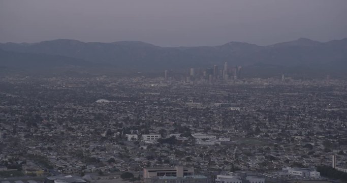 Aerial shot, low light, Downtown Los Angeles and mountains in background, surrounding Los Angeles in foreground, drone
