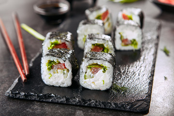 Macro shot of vegetarian sushi rolls with rice, cream cheese, chuka salad, tomato, cucumber and nori. Fresh veggie roll with chopsticks in Japanese restaurant closeup