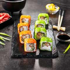 Macro shot uramaki sushi roll with rice, cream cheese, fried shrimp, cucumber, flying fish caviar and nori. Fresh colorful rolls in Japanese restaurant with chopsticks closeup