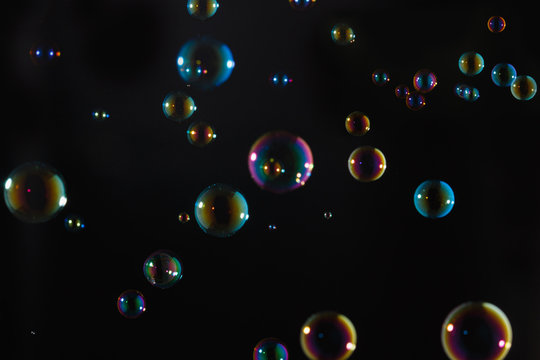 Rainbow soap bubbles colorful float on dark background