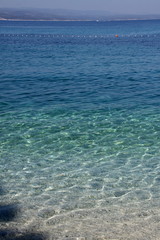 Surface of sea by the gravel beach with line of swimming area