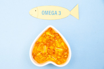 Heart-shape plate with fish oil capsules omega 3, healthy product   and   supplement  concept close up,  flat lay