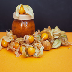Bottles with physalis jam  and fresh  fruit  on orange  background