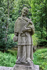 Fototapeta na wymiar Stony sculpture of Saint man with crucifix