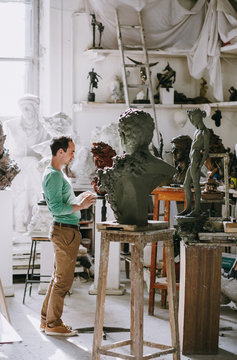 Sculptor examines his work