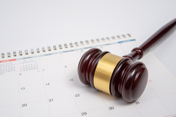 A wooden judge gavel and calendar isolated on white background.