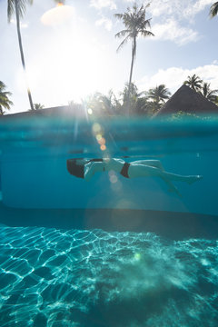 Woman floating in pool water on tropical vacation