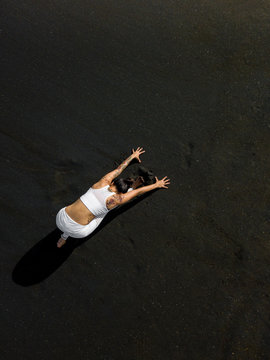 Woman doing yoga exercices on a black beach