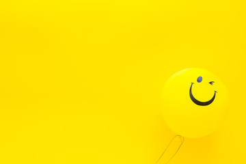 Happiness emotion. Yellow balloon with smile on yellow background top view copy space