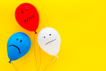 Negative emotions concept. Balloons with drawn faces on yellow background top view space for text