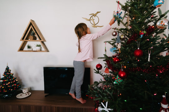 child decorating christmas tree inside home
