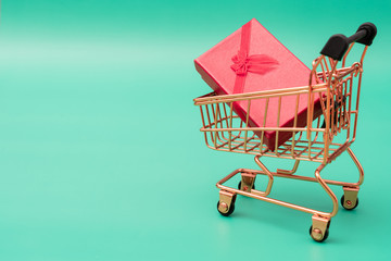 Shopping cart model with a gift box on a green background