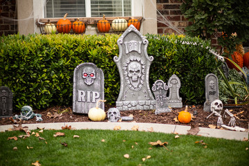 Exterior view of home decorated with Halloween decorations. Skeletons and tombstones and pumpkins cover the front yard of a home.