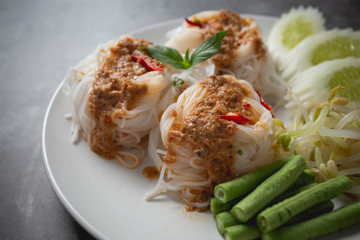 Thai rice noodles in fish curry sauce on wooden table.