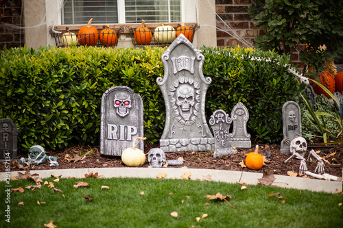 Exterior view of home decorated with Halloween decorations. Skeletons and tombstones and pumpkins cover the front yard of a home.