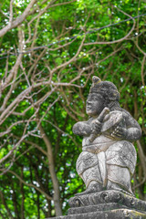 A statue of man wearing a  traditional Bali's clothes, playing a music