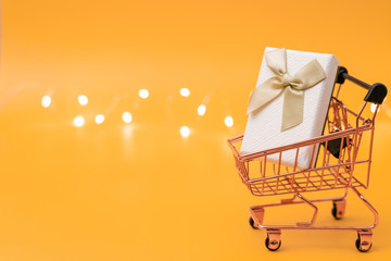 Shopping cart model with gifts on a yellow background