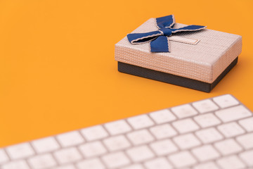 Shopping cart model and computer keyboard with gifts on yellow background