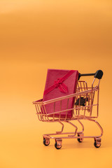 Shopping cart model with gifts in front of yellow background