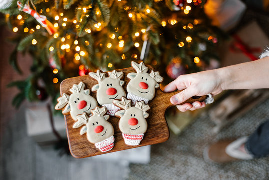 Crop hand with cute gingerbread near Christmas tree