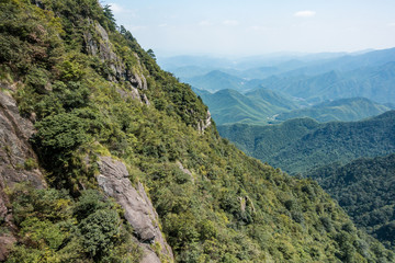 slope on the mountain covered with green forest with forest covered valley in the background on a hazy day