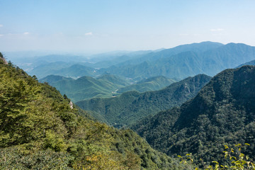 view from the top of a mountain throw the valley floor with forest covered slopes and small villages scatters around on the far end 