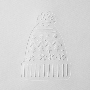 Embossed pattern on a gray cardboard in the form of a hat decorated with snowflakes and Christmas trees with copy space. Layout for Christmas card. Top view