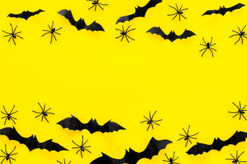 Stylish Halloween design. Bats and spiders on yellow background top view copy space frame