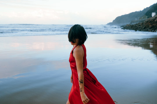 woman in red dress walking on the beach