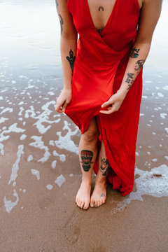woman on the seashore raises her dress so it does not get wet