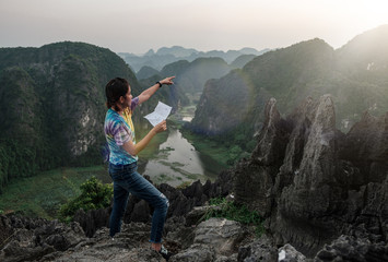 Obraz premium young travelers point to travel through a map in hand. On a scenic hilltop along the way. at Hang Mua, Ninh Bình in Vietnam.
