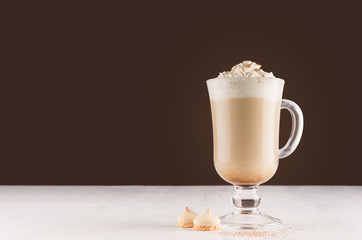 Coffee  in goblet with chocolate powder, foam and biscuits in brown modern restaurant interior, copy space.