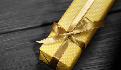 Gift box with ribbon on black wooden background top view.