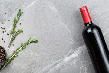 bottle of red wine with spices on gray marble table