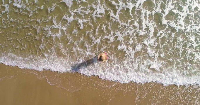 Mujer entra al agua y dron vuela encima en playa dorada