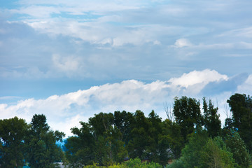 Big and thick clouds on the horizon. Blue sky with thick clouds.