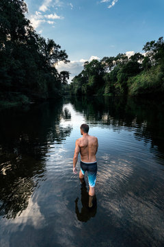 Shirtless man walking in river