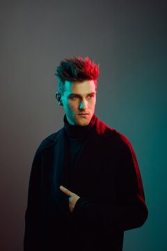Young man wearing trench coat in studio.