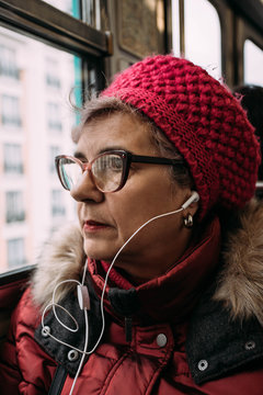 Portrait of a woman riding subway train, listening to music on earbuds