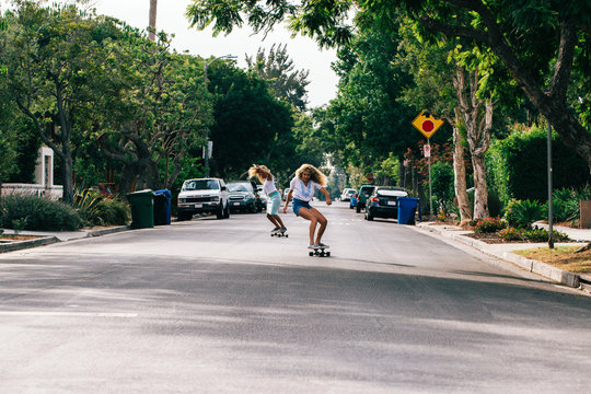Two Young California Girls Skateboarding Sunny Streets of Venice