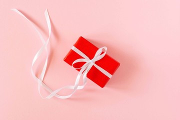Festive background with gift, gift box with ribbon and bow on pink paper