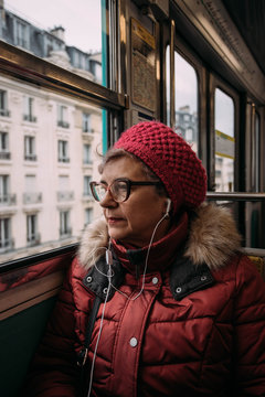Woman riding subway train, listening to music on earbuds